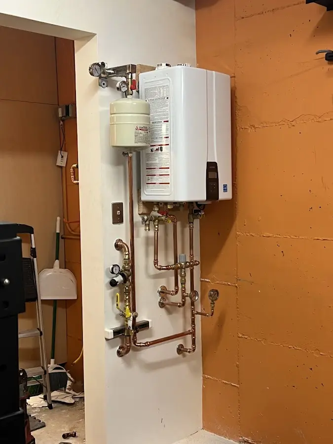 Plumbing technician inspecting water heater connections in St. Clair